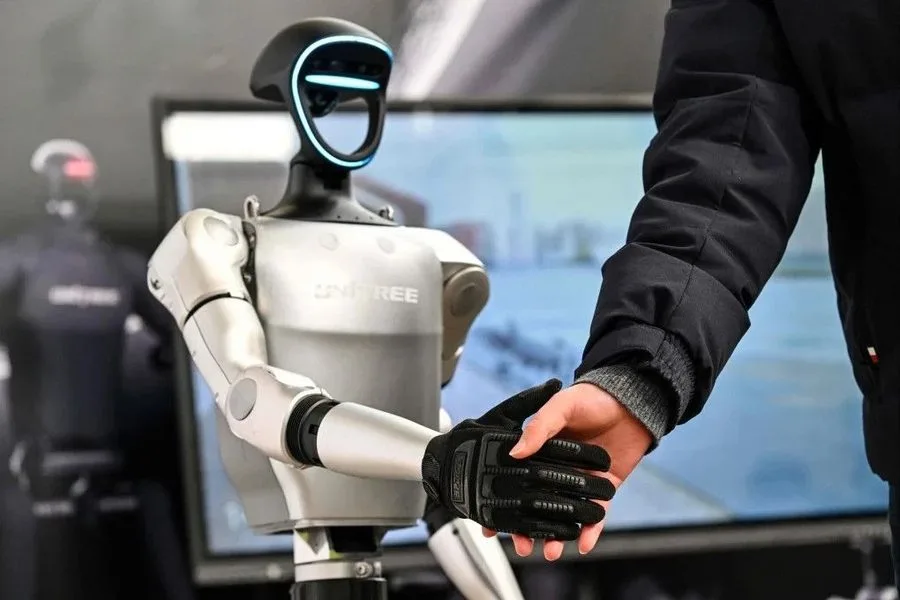 Poignée de main entre un visiteur et un robot humanoïde Unitree G1